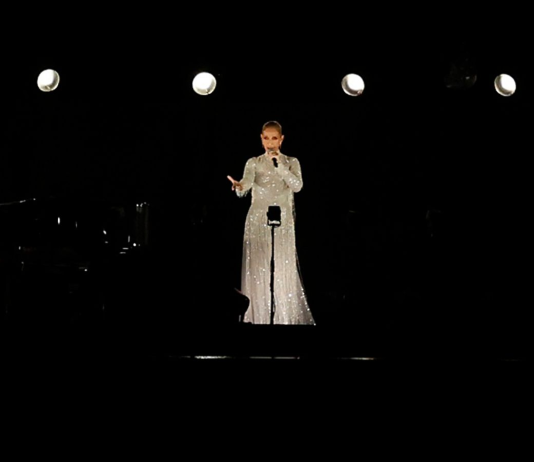 Celine Dion’s Olympic Comeback: A Triumph in Paris Celine Dion performing at the Paris 2024 Olympics, dressed in a white Dior gown, standing on the Eiffel Tower with a backdrop of the Olympic rings.
